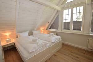 a white bed in a room with windows at Brönswai 5B in Westerland