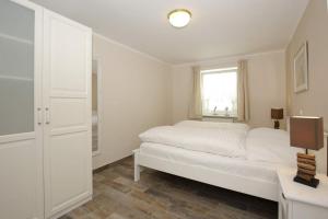 a white bedroom with a bed and a window at Brönswai 5B in Westerland