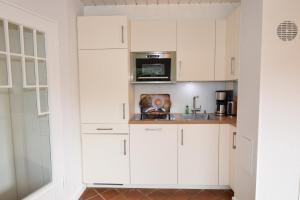 a kitchen with white cabinets and a microwave at Brönswai 5B in Westerland