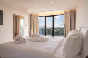 a white bedroom with a large bed with towels on it at Megara Hotel in Megara