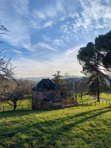 a stone building in a field with a fence at Gite a collonges la rouge avec spa in Collonges