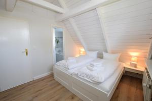a white bedroom with a bed with white sheets at Brönswai 5A in Westerland
