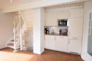 a kitchen with white cabinets and a staircase at Brönswai 5A in Westerland