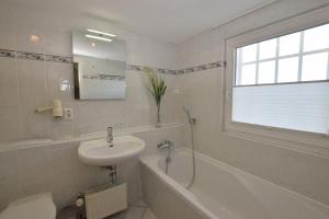 a white bathroom with a sink and a tub and a sink at Brönswai 5A in Westerland