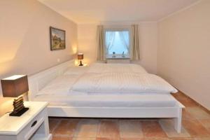 a white bedroom with a large bed and a window at Brönswai 5A in Westerland