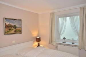 a white bedroom with a bed and a window at Brönswai 5A in Westerland +15 photos