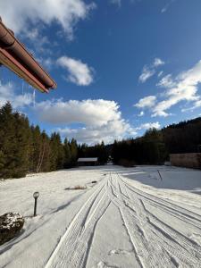 a snow covered road with a house in the background at Leśna Przystań in Sidzina