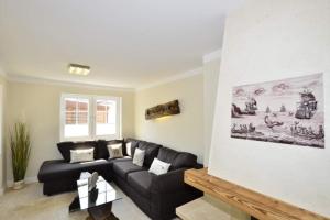 a living room with a black leather couch at Ferienhaus Litj Stig in Westerland