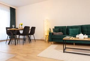a living room with a green couch and a table at Luxus Apartament Róża in Gdynia