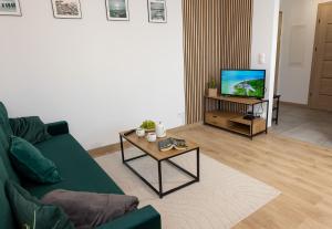 a living room with a green couch and a tv at Luxus Apartament Róża in Gdynia