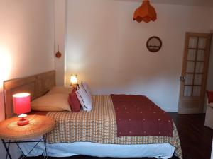ein Schlafzimmer mit einem Bett und einem Tisch mit einer Lampe in der Unterkunft Le Micolo in Mailly-le-Château