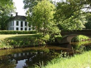 a house with a bridge and a river in front at B&B de Trochset in Balk