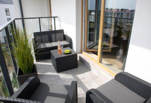 a balcony with chairs and a table with a bottle of wine at Luxus Apartament Róża in Gdynia