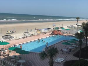 a swimming pool next to a beach with people in it at Harbour Beach Resort in Daytona Beach