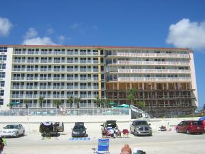 a large building on the beach with cars parked in front at Harbour Beach Resort in Daytona Beach