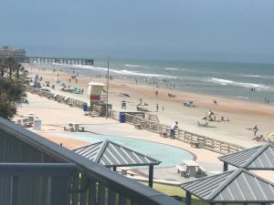 a beach with a group of people and the ocean at Harbour Beach Resort in Daytona Beach +2 photos