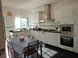 a kitchen with white cabinets and a table with chairs at Casa D Dinis by NaturAlegre in Alegrete