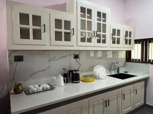a kitchen with white cabinets and a counter top at Writer's Inn in Vaikom