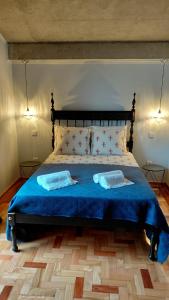 a bedroom with a blue bed with two pillows at Casas do Pargo - Casa B Palheiro in Ponta do Pargo