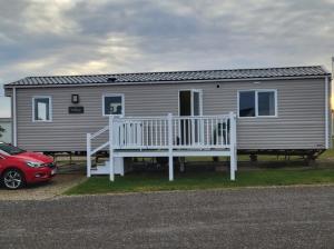 a house with a porch and a car parked in front of it at Silversands - Private Caravan Let in Lossiemouth
