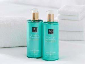 two green bottles of soap sitting next to towels at Novotel Rouen Sud Zenith Parc Expo in Saint-Étienne-du-Rouvray +73 photos