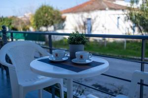 a table with two cups and a potted plant on a balcony at Villa Papazoglou in Neos Pirgos