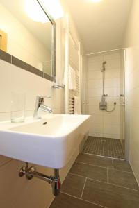 a white bathroom with a sink and a shower at Pension Plangger in Pfunds