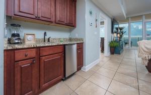 a kitchen with wooden cabinets and a tile floor at Phoenix Gulf Shores 1602 in Gulf Shores