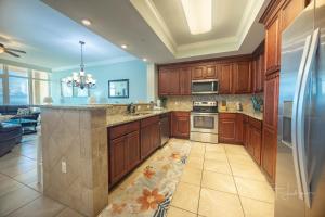 a large kitchen with wooden cabinets and a stove at Phoenix Gulf Shores 1602 in Gulf Shores