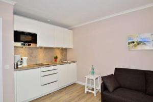 a kitchen with white cabinets and a couch in a room at Eydum, App 45 in Westerland