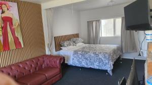 a bedroom with a bed and a couch and a television at Rattrays Rd Farm Accomodation in Makikihi
