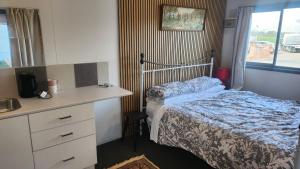 a bedroom with a bed and a dresser and a desk at Rattrays Rd Farm Accomodation in Makikihi