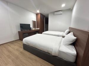a hotel room with two beds and a television at J&P Hotel Sriracha in Ban Laem Chabang