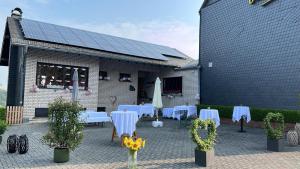 a patio with white tables and chairs and a building at Zur Kringelwies in Masburg