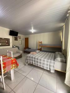 a bedroom with a bed and a couch and a tv at Casa de descanso, completa, para ate 05 pessoas in Pântano Grande