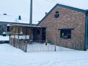 a brick building with a fence in the snow at L Abri douillet in Libin +45 photos