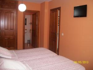 een slaapkamer met een bed en een flatscreen-tv aan de muur bij La Casa del Reloj in Enciso