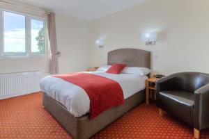 a bedroom with a bed and a leather chair at Wayford Bridge Inn Hotel in Stalham