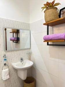 a bathroom with a sink and a mirror and purple towels at Sophie Homestay in Moshi