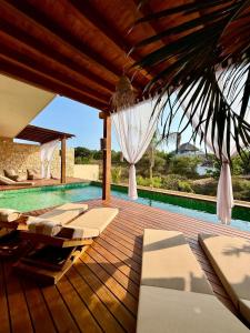 an outdoor deck with lounge chairs and a swimming pool at Luxury Ocean View Villa in Brisas de Zicatela