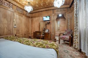 a bedroom with a bed and a chair at Alexandra Houseboats in Srinagar