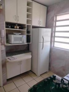 a kitchen with white cabinets and a white refrigerator at apartamento atras do shopping Iguatemi 2 quartos in Votorantim