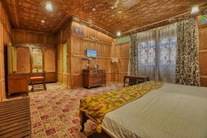 a bedroom with a bed and a desk and a television at Alexandra Houseboats in Srinagar
