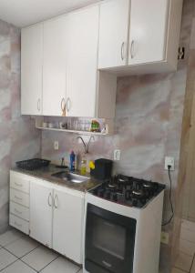 a kitchen with white cabinets and a stove top oven at apartamento atras do shopping Iguatemi 2 quartos in Votorantim