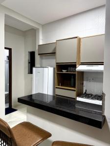 a kitchen with a black counter top and a refrigerator at Pousada & Flat Brandão - Canindé de São Francisco, SE in Canindé de São Francisco