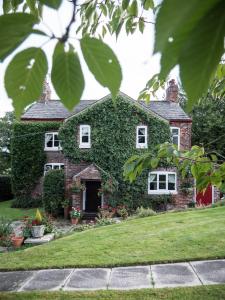 a brick house with ivy on it at Ash Farm Country House in Little Bollington