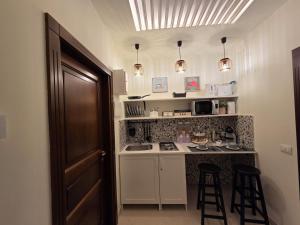 a small kitchen with a counter and two bar stools at Erbanova al Borgo Suite in Taranto +17 photos