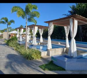 a row of white umbrellas next to a pool at Apto com área de lazer estilo resort in Parnamirim