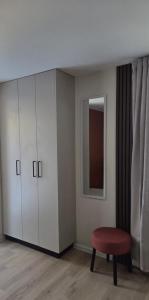 ein Zimmer mit einem weißen Schrank und einem roten Hocker in der Unterkunft Atari Apartment in Ropažu Sala