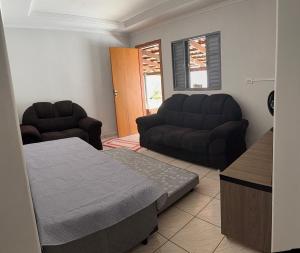 a living room with a bed and a couch at Suítes Santa Luzia in Trindade